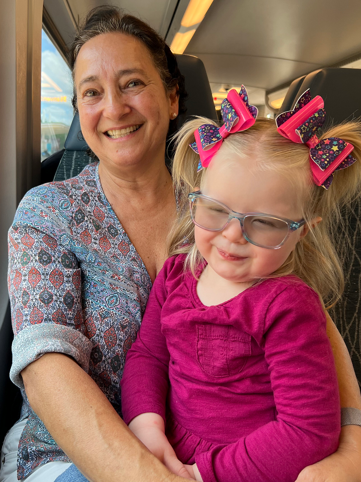A woman and a little girl sit together on a train.